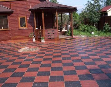 Площадка возле дома мощенная тротуарной плиткой 8 кирпичей сочетанием цветов красный и черный в шахматном порядке